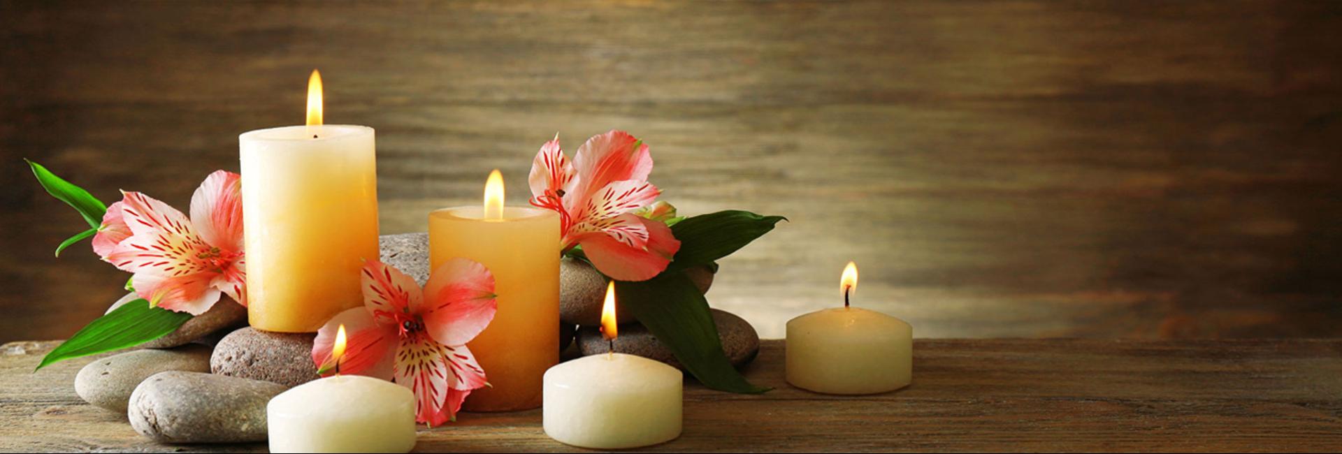 Candele accese con fiori rosa su sfondo di legno, atmosfera rilassante.