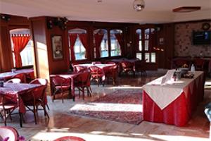 Ristorante elegante con arredi rossi, tavoli apparecchiati e luce naturale abbondante.