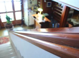 Vista dall'alto di una scala con corrimano in legno, ambiente accogliente.