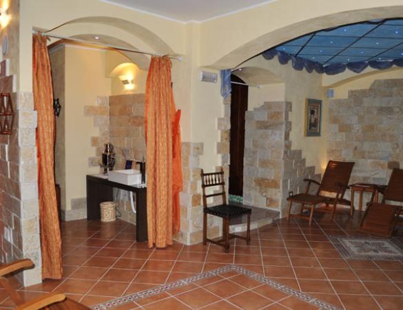 Sala relax con sedie a sdraio, tende arancioni e decorazioni in pietra.