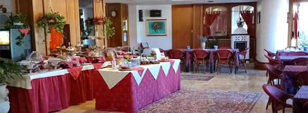 Sala da pranzo con buffet, tavoli apparecchiati e decorazioni eleganti.