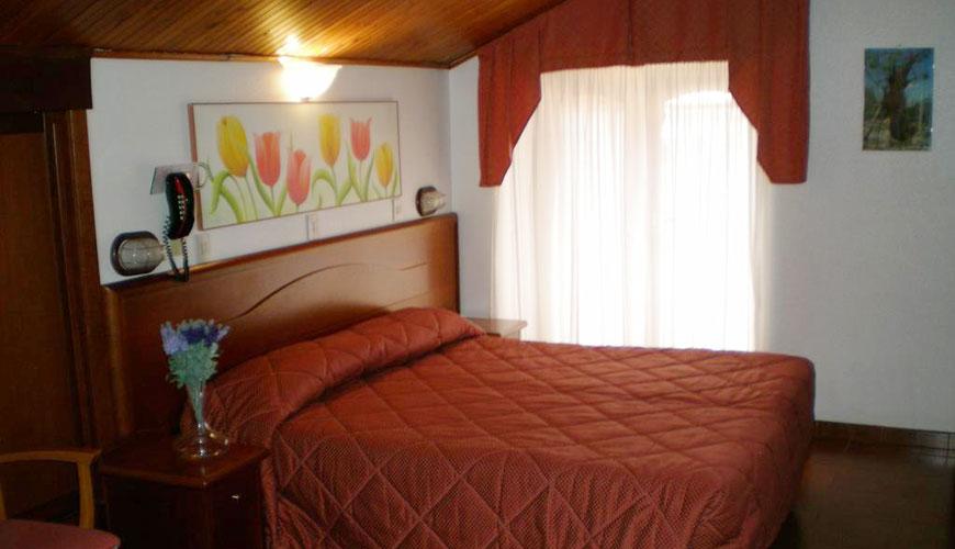 Camera da letto con letto matrimoniale, decorazioni floreali e tenda rossa.
