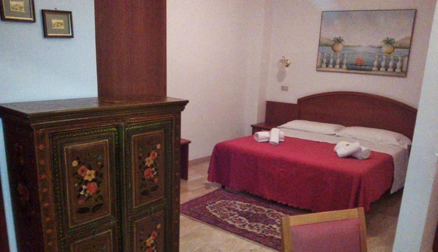 Camera accogliente con letto matrimoniale, armadio decorato e dipinto murale.